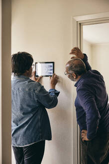 Älteres Ehepaar betrachtet die Heimautomatisierung an der Wand - MASF36049