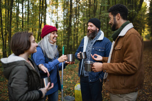 A diverse group of happy volunteers cleaning up forest, having break, drinking tea and talk together. - HPIF07116