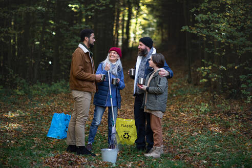 A diverse group of happy volunteers cleaning up forest, having break, drinking tea and talk together. - HPIF07117