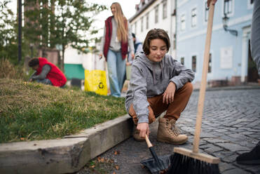 Ein Mädchen im Vorschulalter, das freiwillig mit einem Team die Straße säubert, Konzept der gemeinnützigen Arbeit - HPIF07144