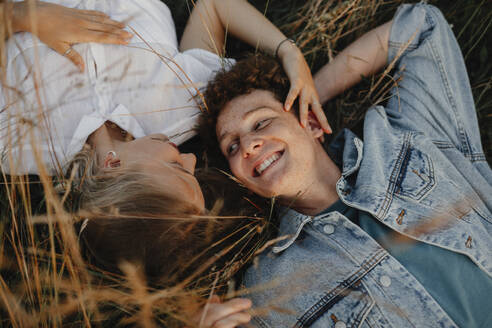 A top view of young couple on a walk in nature in countryside, lying in long grass. - HPIF07161