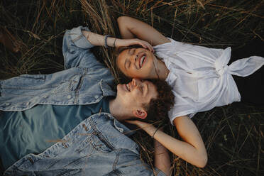 Ein junges Paar auf einem Spaziergang in der Natur auf dem Land, im Gras liegend und lachend. - HPIF07163