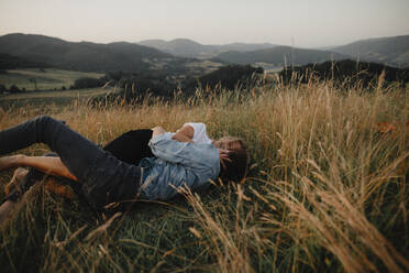 Ein junges Paar auf einem Spaziergang in der Natur, das im Gras liegt und Spaß hat. - HPIF07168