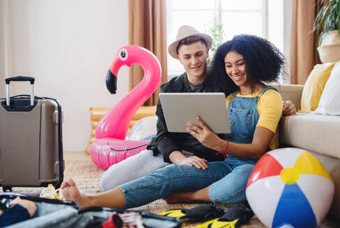 Happy young couple with tablet packing for holiday at home. - HPIF07202