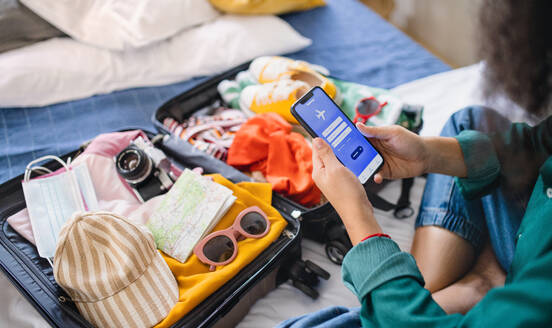 Unrecognizable young woman with suitcase packing for holiday at home, coronavirus concept. - HPIF07227