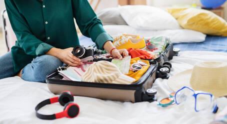 Unrecognizable young woman with suitcase packing for holiday at home, coronavirus concept. - HPIF07229