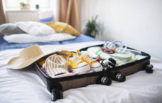 Ein offener, für den Urlaub gepackter Koffer auf dem Bett zu Hause, Coronavirus-Konzept. - HPIF07232