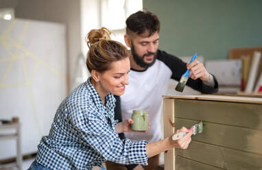 Happy mid adults couple painting furniture indoors at home, relocation and diy concept. - HPIF07235