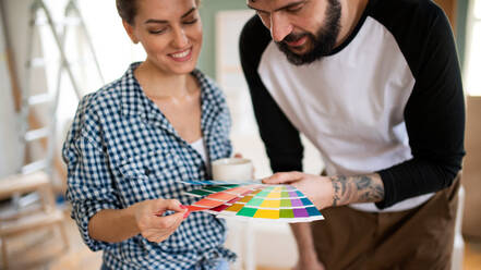 Front view of mid adults couple with colour swatch indoors at home, relocation and diy concept. - HPIF07241