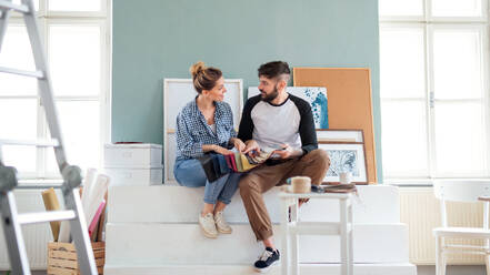 Frontansicht eines erwachsenen Paares mit Farbmuster im Haus, Umzug und Diy-Konzept. - HPIF07243
