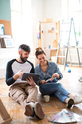 Front view of mid adults couple planning with tablet indoors at home, relocation and diy concept. - HPIF07252