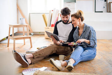 Front view of mid adults couple planning with tablet indoors at home, relocation and diy concept. - HPIF07253