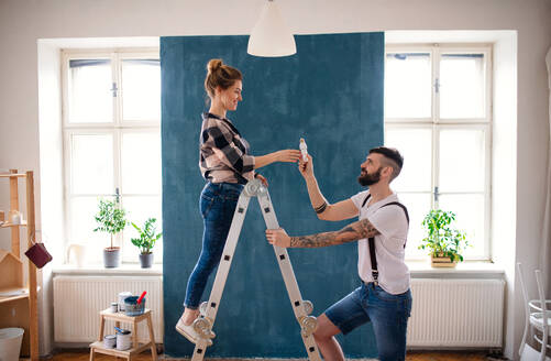 Happy mid adults couple changing light bulb indoors at home, relocation and diy concept. - HPIF07273