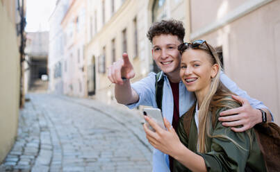 A young couple travelers using smartphone in city on holiday, sightseeing. - HPIF07304