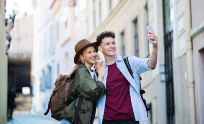 Ein junges Paar, das seinen Urlaub in der Stadt genießt und seine Erinnerungen mit einem Selfie auf seinem Smartphone festhält - HPIF07309