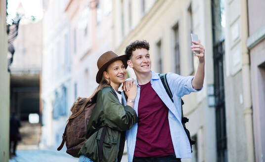 A young couple enjoying their holiday in the city, capturing memories with a selfie using their smartphone - HPIF07309