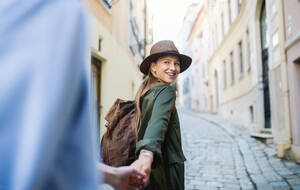 A young couple travelers in love sightseeing in city on holiday, holding hands when walking. - HPIF07310