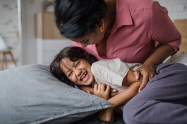Eine glückliche Mutter kitzelt ihren kleinen Sohn, wenn sie ihn morgens aufweckt. - HPIF07332