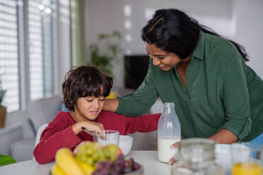 Ein glücklicher kleiner Junge, der mit seiner Mutter zu Hause frühstückt. - HPIF07339