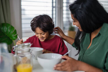A happy little boy having breakfast with his mother at home. - HPIF07341