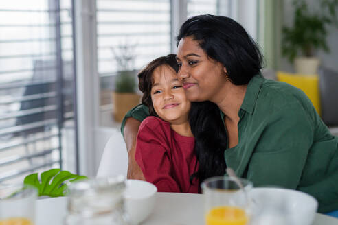 Ein kleiner Junge umarmt seine Mutter beim Frühstück zu Hause. - HPIF07343