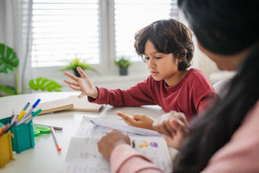 A little multiracial boy doing homework with his mother at home. - HPIF07346