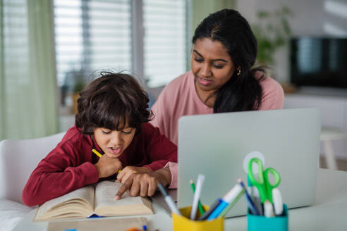 Eine indische Mutter mit ihrem kleinen Sohn, der einen Laptop benutzt und zu Hause Online-Schulunterricht hat. - HPIF07349