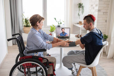 Behinderte Menschen, die zu Hause am Tisch sitzen, Video-Online-Konsultation mit dem Arzt. - HPIF07378