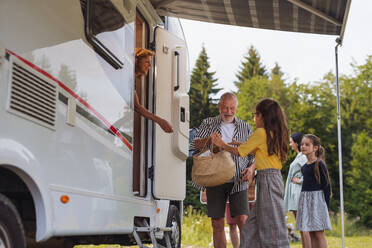 Glückliche Mehrgenerationen-Familie beim Auspacken und Reden im Auto, Urlaubsreise mit dem Wohnwagen. - HPIF07403