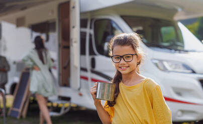 Ein glückliches kleines Mädchen steht im Freien und schaut in die Kamera am Wohnwagen, Familienurlaub. - HPIF07406