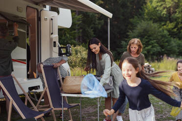 Glückliche Mehrgenerationen-Familie beim Auspacken und Reden im Auto, Urlaubsreise mit dem Wohnwagen. - HPIF07409