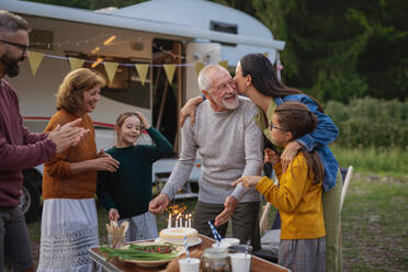 Ein älterer Mann feiert seinen Geburtstag im Freien auf einem Campingplatz, eine Mehrgenerationen-Familienreise im Wohnwagen. - HPIF07431