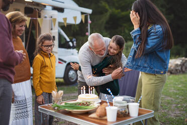 Ein kleines Mädchen feiert seinen Geburtstag im Freien auf einem Campingplatz, eine Mehrgenerationen-Familienreise im Wohnwagen. - HPIF07436