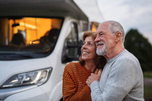 Ein älteres Paar, das sich in der Abenddämmerung im Freien umarmt, Urlaub im Wohnwagen. - HPIF07449