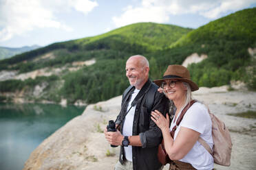 Ein glückliches älteres Paar beim Wandern im Sommerurlaub, das die Landschaft betrachtet. - HPIF07459