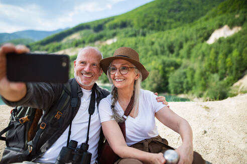 A joyful elderly couple captures their summer hiking adventure with a selfie - HPIF07466