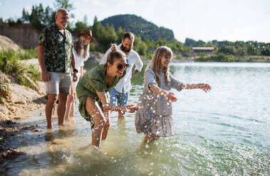 A happy multigeneration family on walk by lake on summer holiday, having fun in water. - HPIF07471