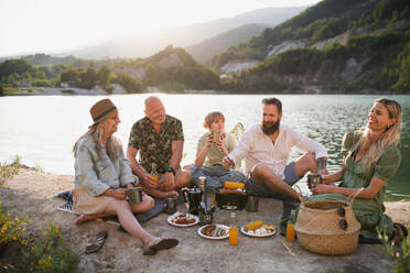 Eine glückliche Mehrgenerationenfamilie auf Sommerurlaubsreise, Grillparty am See. - HPIF07479