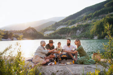 A happy multigeneration family on summer holiday trip, barbecue by lake. - HPIF07483