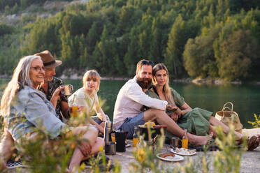 A happy multigeneration family on summer holiday trip, barbecue by lake. - HPIF07487