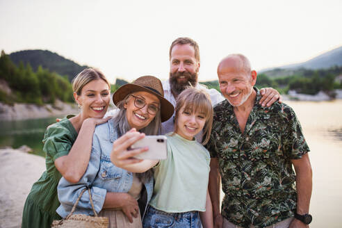 Eine fröhliche Familie unterschiedlichen Alters, die eine gemeinsame Sommerwanderung genießt und den Moment mit einem Selfie festhält - HPIF07510