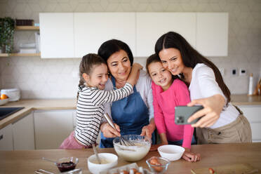 Drei Generationen von Frauen, die beim Pfannkuchenbacken zusammenkommen und ihre Erinnerungen mit einem lustigen Selfie zu Hause festhalten - HPIF07515