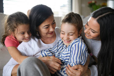 Portrait of happy small girls with mother and grandmother indoors at home, hugging. - HPIF07527