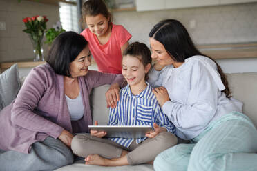 Portrait of happy small girls with mother and grandmother indoors at home, using tablet. - HPIF07529