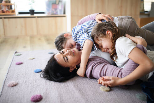 Fröhliche kleine Mädchen mit ihrer älteren Großmutter zu Hause, die im Schlafzimmer auf dem Boden spielen. - HPIF07534