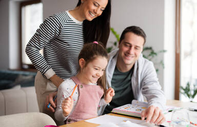 Eltern mit Schulmädchen drinnen zu Hause, Fernstudium und Home-Office-Konzept. - HPIF07538