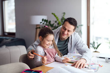 Father helping small daugther with homework indoors at home, distance learning. - HPIF07539
