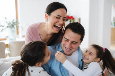 Portrait of cheerful parents with small daughters indoors at home, having fun. - HPIF07554