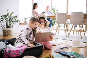 Glückliche kleine Mädchen mit Tablet im Haus, die für den Sommerurlaub packen. - HPIF07560