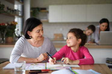 A small girl with grandmother doing homework indoors at home. - HPIF07566